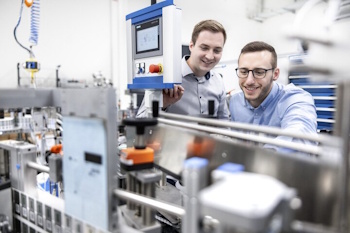 Two men are jointly examining a machine control panel in a modern production environment.