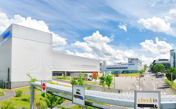 Modern buildings with clean lines against a blue sky. Traffic signs indicate check-in and other directions.