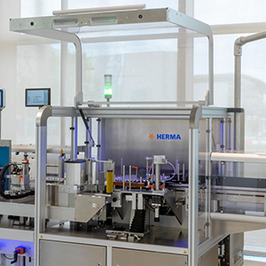 Automatic labeling machine from HERMA with various components for labeling and packaging.