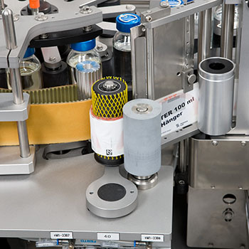 Machine for labeling bottles with various labels and containers in an industrial setting.