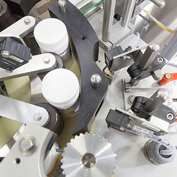 Machine for labeling bottles, featuring various mechanical components and sensors for precise handling.