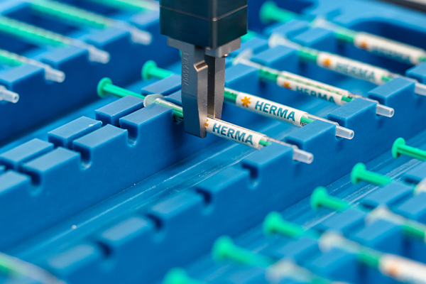 A syringe is labeled and moved with a robotic gripper.