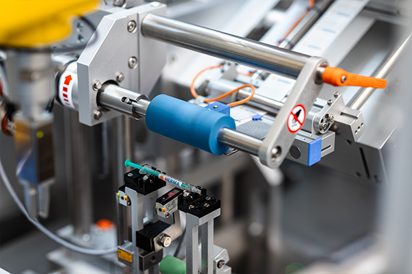 Automated machine components featuring a blue cylinder and various grippers for handling objects in an industrial setting.