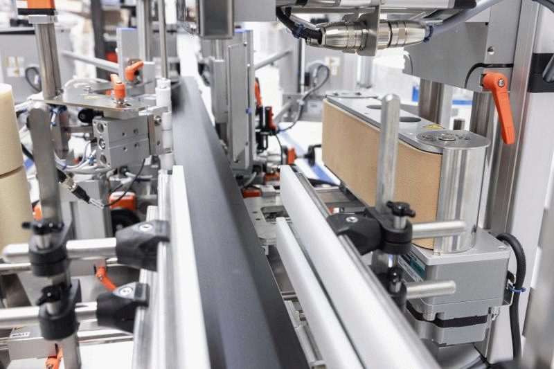 Automated machines for packaging, equipped with conveyor belts and various mechanical components for handling products.