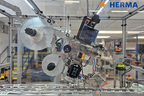 Automated labeling machine with rollers and control unit in a production environment.