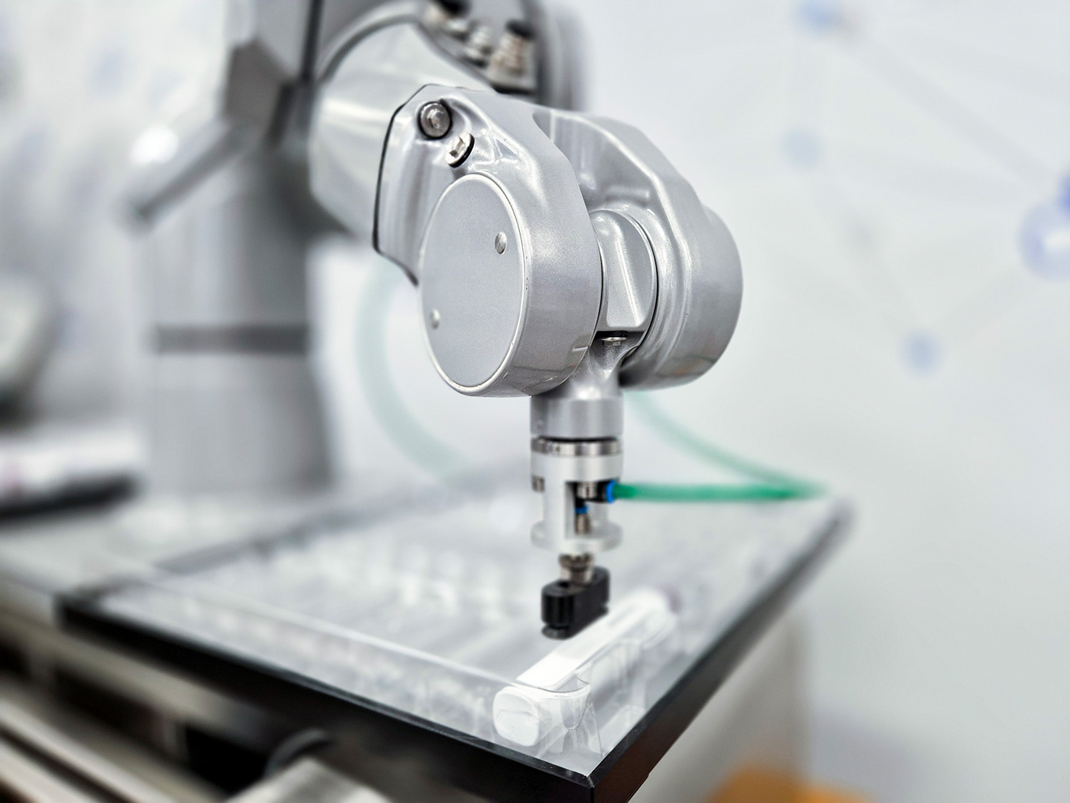 Industrial robotic arm with a gripper, positioned on a transparent surface, ready to grasp an object.