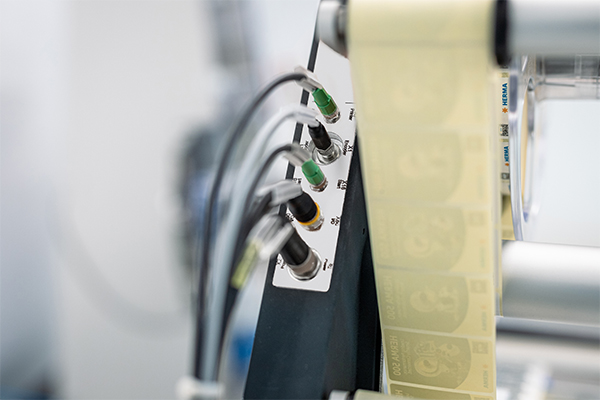 Control unit with multiple connections and a roll of labels in an industrial setting.