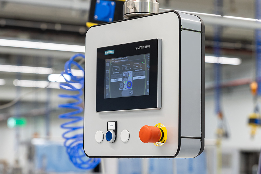 Control panel with a touchscreen and control buttons, used for operating machines in an industrial setting.