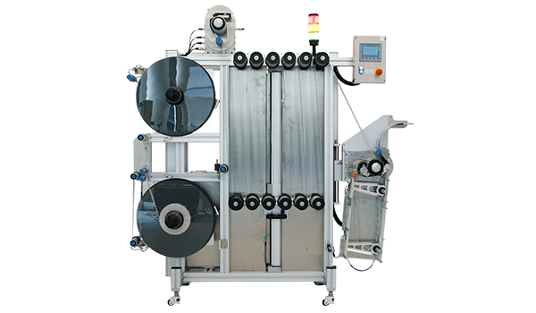 An industrial packaging machine with two large rolls, a control unit, and an output area for packaged products.