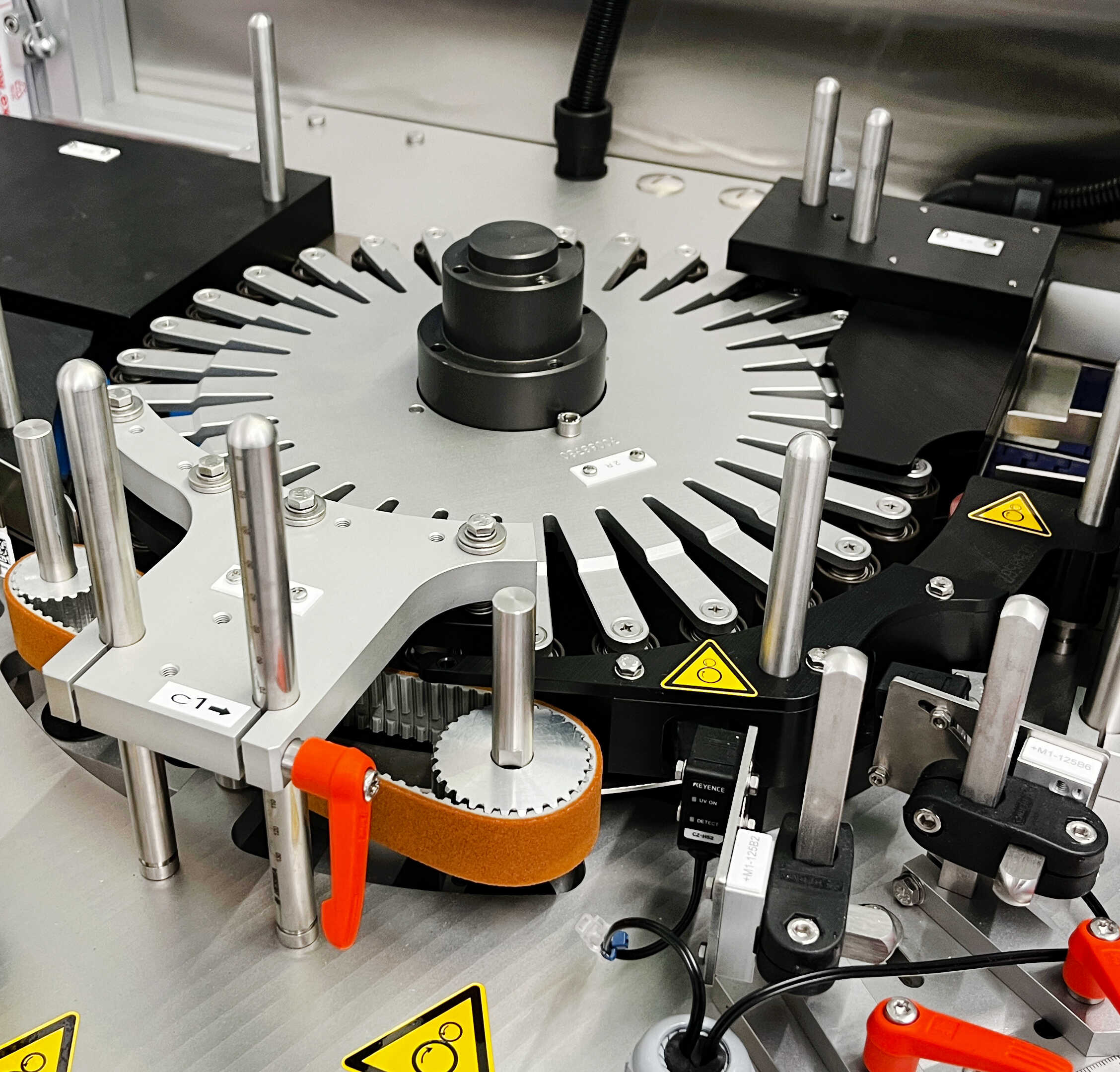 Machine with a rotating plate system, equipped with multiple holders and safety warnings.