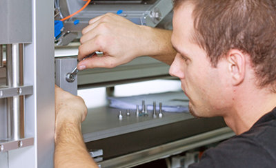 A technician is working with a wrench on a machine component to assemble or repair it.