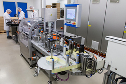 A bottling facility in a production site with employees in protective gear handling and monitoring bottles.