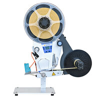 A labeling machine with a large spool and a black ribbon, equipped with a control panel and a sturdy base.