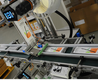 A production line with a conveyor belt where products are moved with labels and a scanner for quality control.