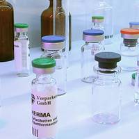A collection of glass vials with various cap colors, some labeled, used for packaging and laboratory purposes.