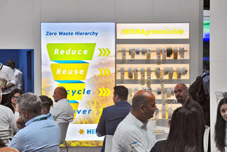 Two information boards at a trade fair, one featuring the Zero Waste Hierarchy and the other showcasing the HERMAgreenGuide.