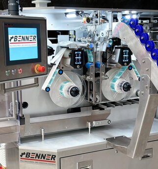 Labeling machine with two roll holders and a control panel, equipped with a screen and control buttons.