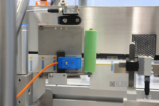 Labeling machine with sensors and a green roller mechanism that applies labels to products.