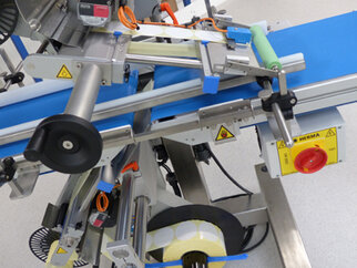 A packaging machine with a conveyor belt, rollers, and control elements designed for industrial applications.
