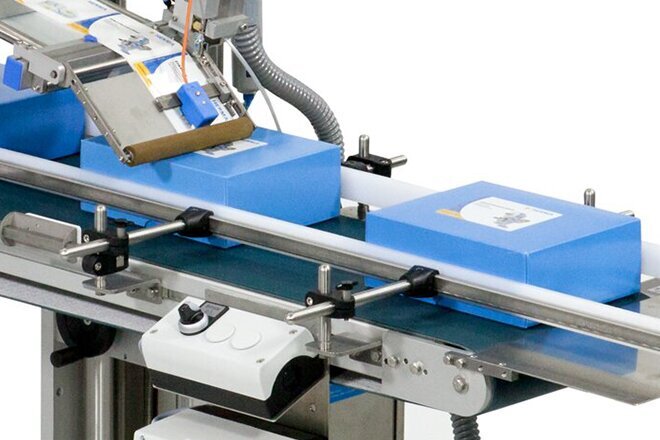 A packaging machine with blue boxes on a conveyor belt, used for automating packaging processes.