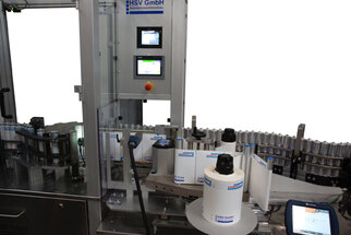 Automatic labeling machine with multiple rolls, control unit, and labels for bottles.