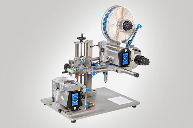 A labeling machine with various components for applying labels to products. It is mounted on a sturdy table.