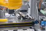 Industrial robotic arm with a gripping mechanism that processes objects on a conveyor belt. Technical components and sensors are visible.