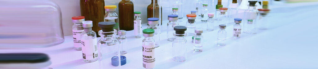 A variety of different glass bottles with colorful caps on a table, some containing liquids while others are empty.